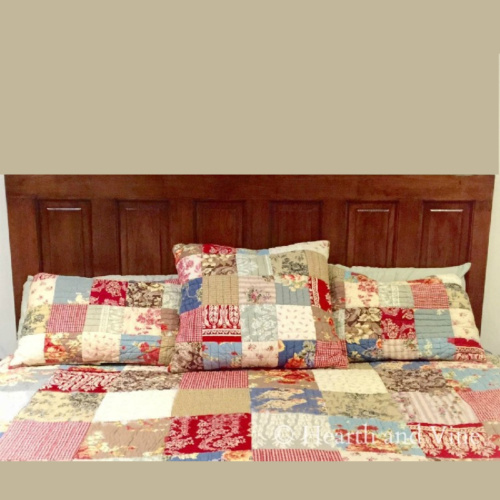 Wood door headboard on wall with multi-colored-quilt on bed.