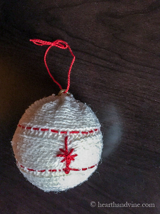 Upcycled embroidered sweater ornament with red thread.
