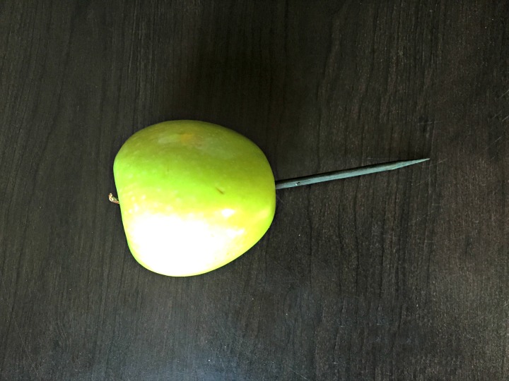 Green apple with wooden stick inserted
