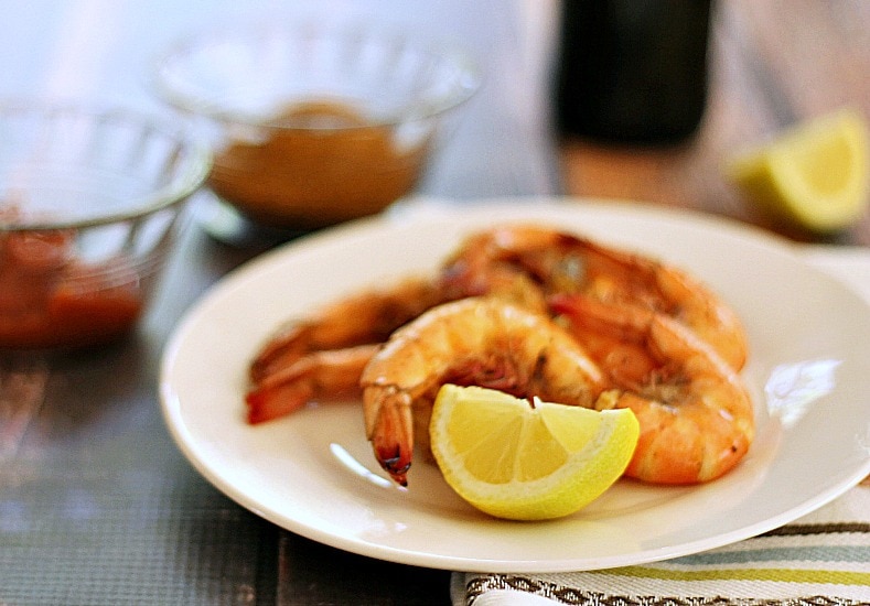 Steamed shrimp on a plate with a wedge of lemon.