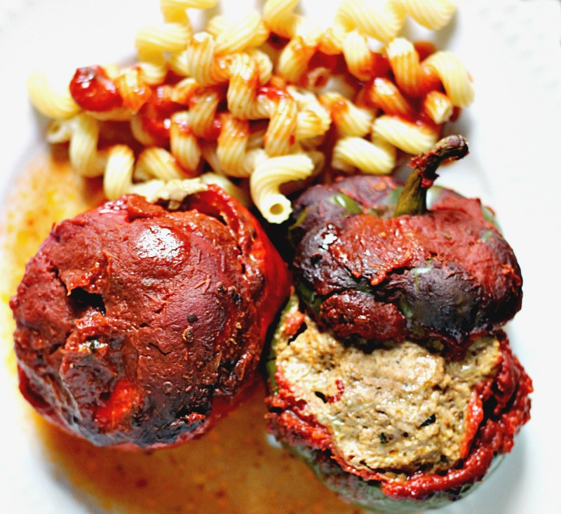 Cooked meatball stuffed peppers with sauce and pasta on plate