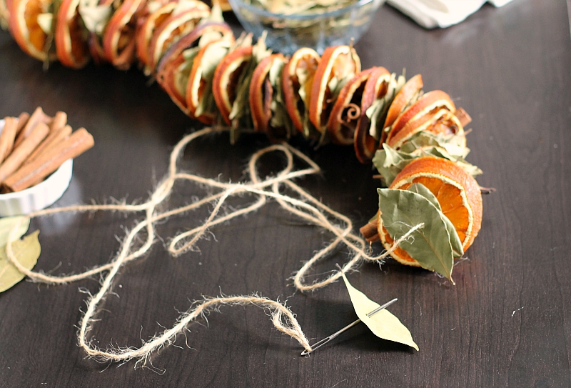 Stringing bay leaf on orange garland