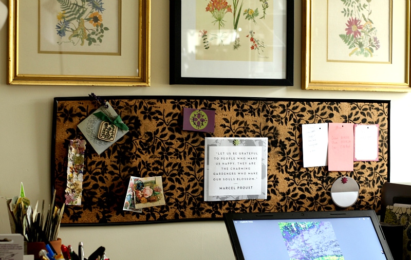 Black floral cork bulletin board hung horizontal on a wall.