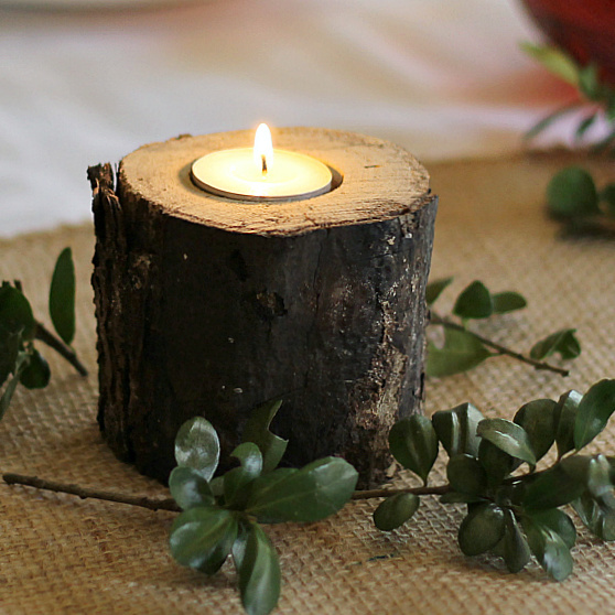 Log candle holder with a tealight and some boxwood surrounding the base.