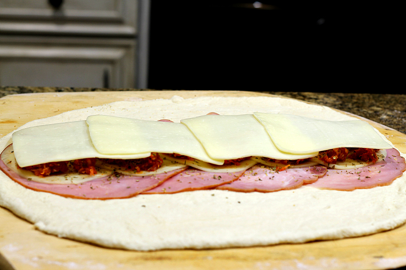 Italian meats and cheeses layered on pizza dough.