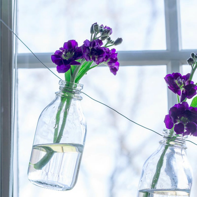 Glass bottle vase garland with purple flowers