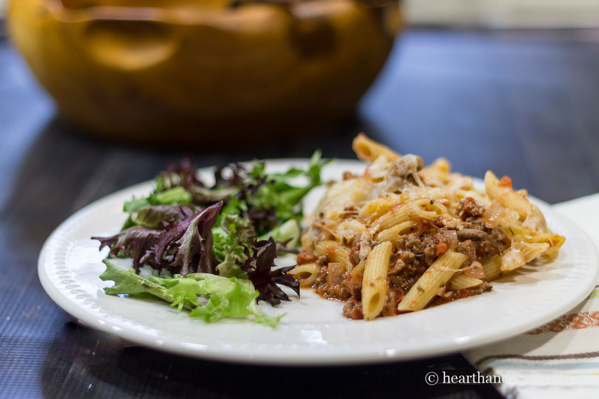 White dinner plate with salad and a serving of spaghetti casserole.