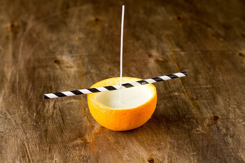 Straw holding a week on an orange peel candle.