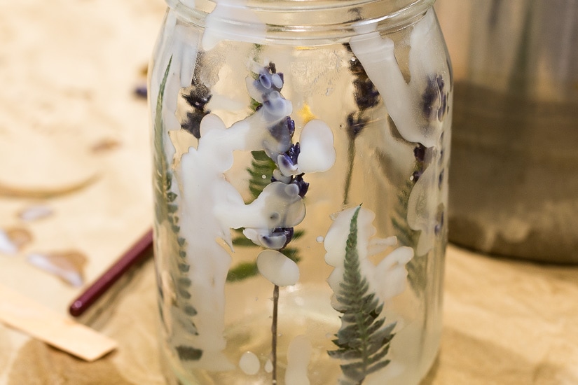 Additional wax on lavender flowers and ferns inside the jar.