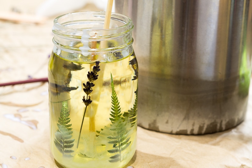 Fresh wax poured into mason jar with pressed flowers on sides.