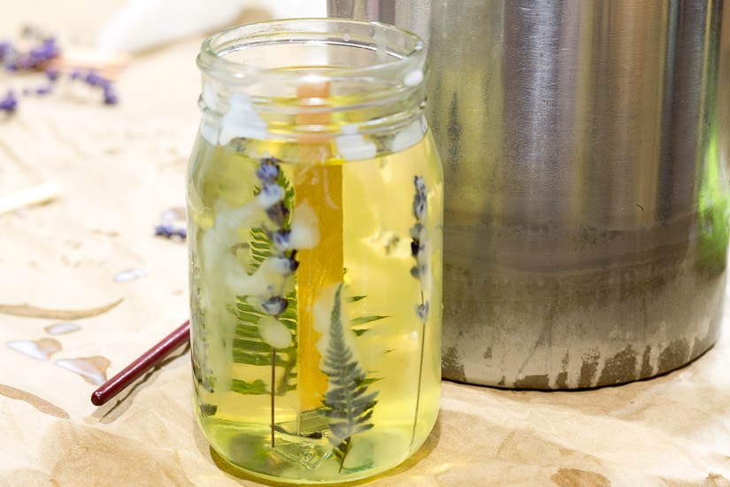 Fresh wax poured into mason jar with pressed flowers on sides.