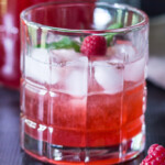 Cocktail glass with raspberry shrub mix, ice, fresh raspberries and mint.