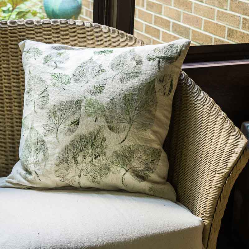 Leaf print drop cloth pillow on couch in screened in porch.