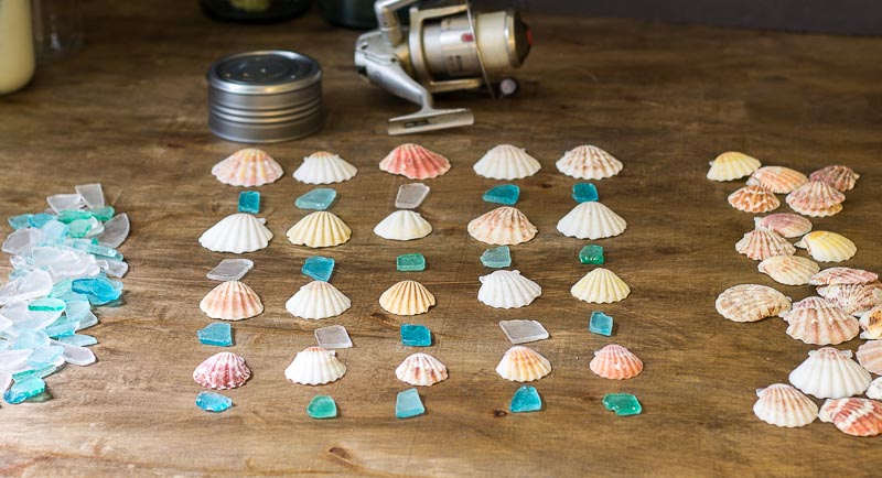 Seashells and seaglass laid out in a pattern to make the wind chime.