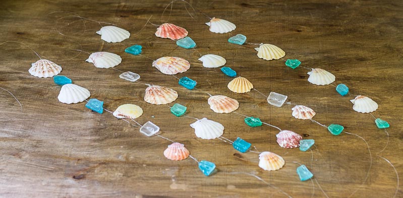 Five strands of seashells and seaglass on fishing line for the DIY wind chime.