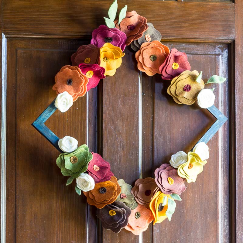 Wooden frame painted blue with autumn colored felt flowers glued at the top and bottom.