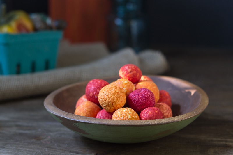 Fragrant orange and red soap balls in a wooden bowl.