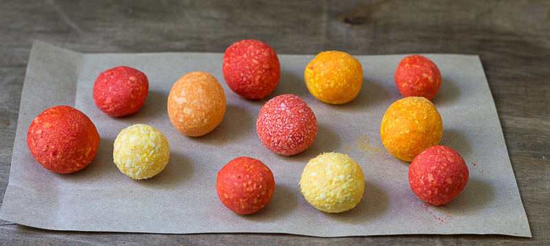 Soap balls in shades of yellow and orange drying on a piece of cardboard.