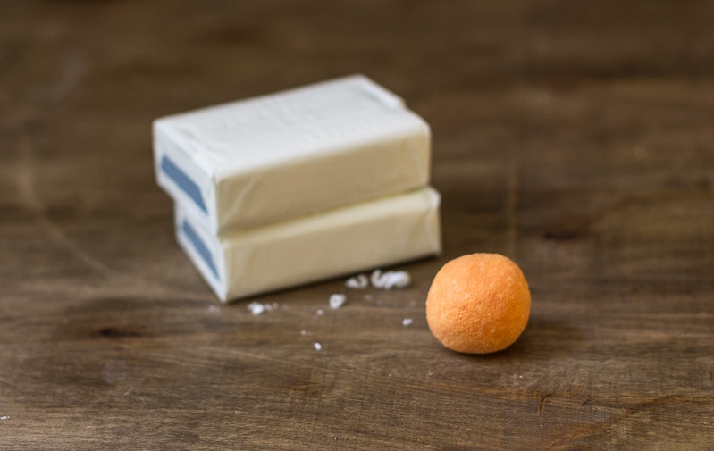 Bars of soap next to a small orange soap ball.