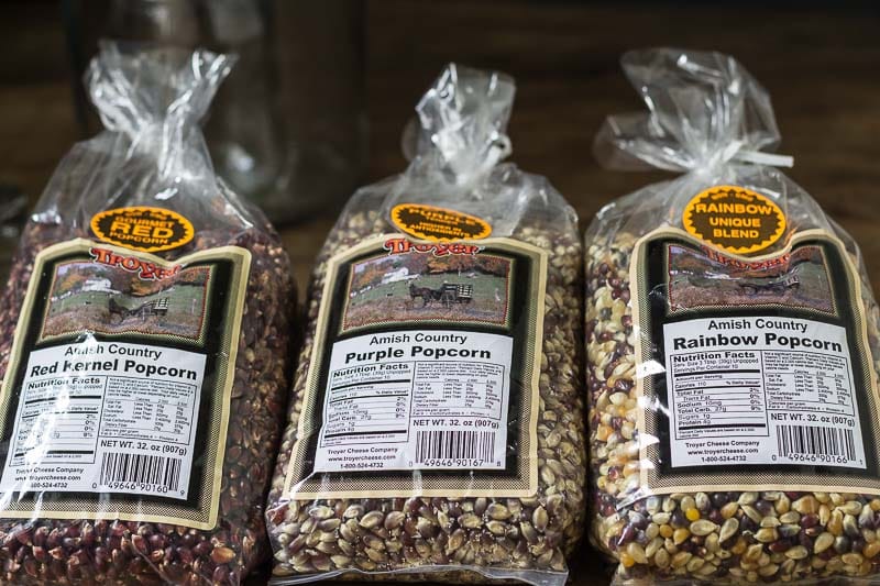 Three different bags of colored popcorn kernels, red, purple and rainbow.