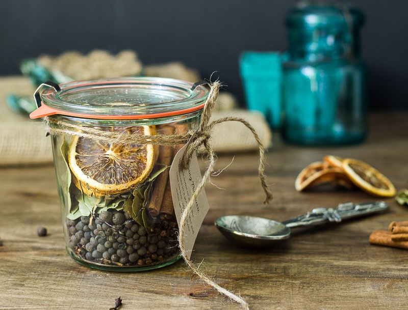 Stove top potpourri jar with instruction tag next to a decorative spoon.