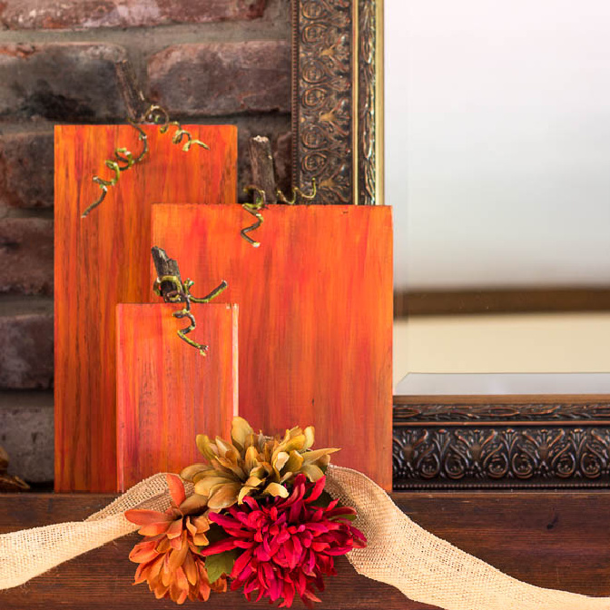 Three wooden pumpkins on a mantel.