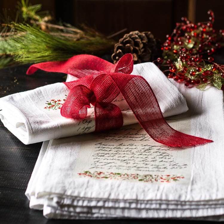 Two family cookie recipe on a white tea towels folded and wrapped with a red ribbon.