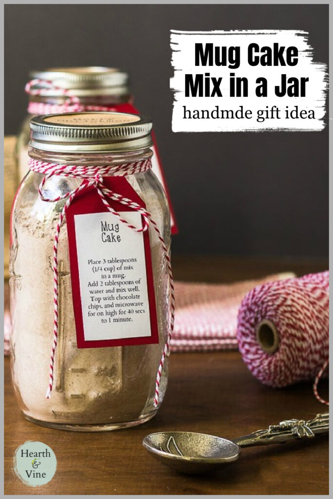 A mason jar with mug cake mix next to a ornate spoon and a spool of red and white stripped twine.