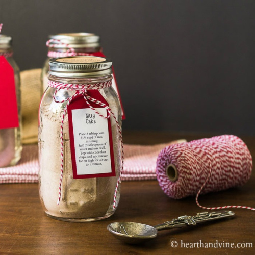Mug cake mix in a mason jar with a red backed instruction tag tied on with red and white twine.