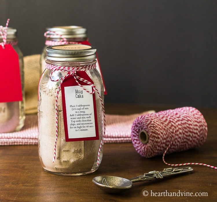 Mason jar with mug cake mix red and white string and a decorative spoon.