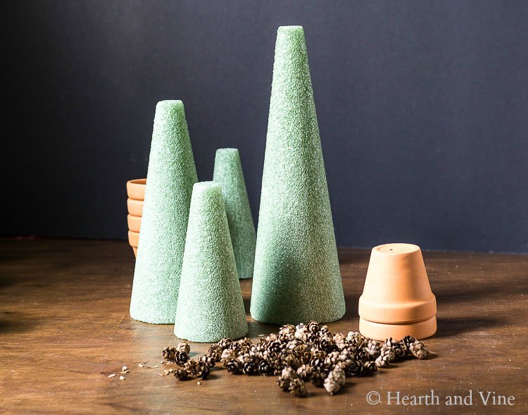 Green styrofoam cones, mini pine cones and small terra cotta pots.