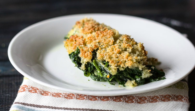 Serving of creamy spinach casserole on a white plate.