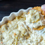 Cracker dipped in crab and artichoke dip.