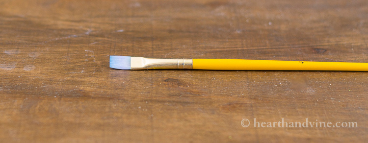 Using a flat paint brush helps create lines.