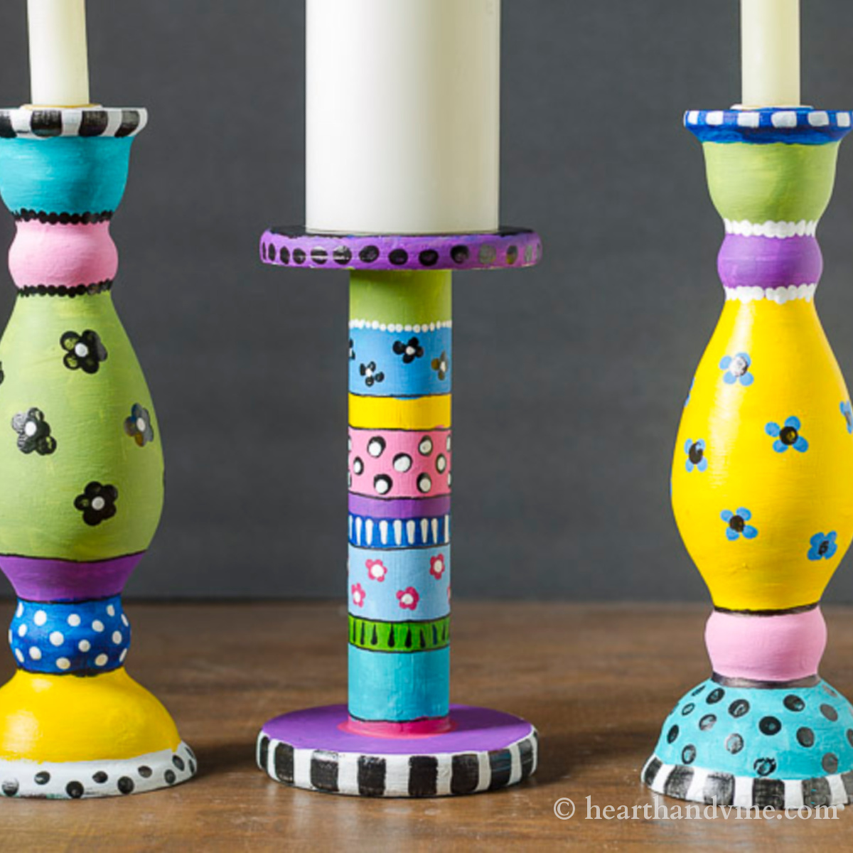 Three brightly decorated wooden candlesticks with paint.
