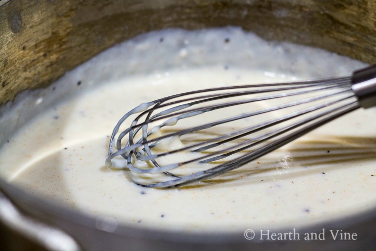 White sauce in pan with whisk