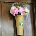 Peonies in a burlap vase on door.