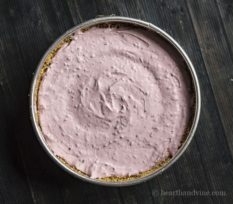 Berry cheesecake filling in graham cracker crust spring form pan.