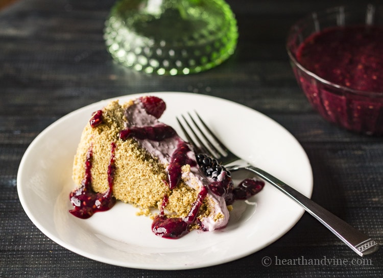 Slice of no sugar added berry cheesecake with berry puree sauce.