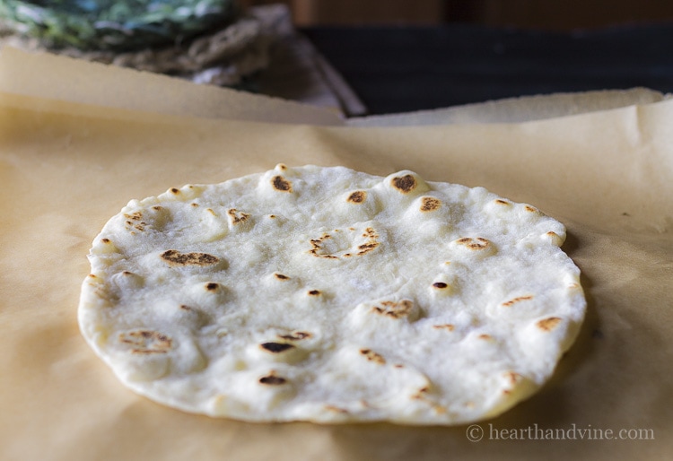 Homemade flour tortillas separated by parchment paper.