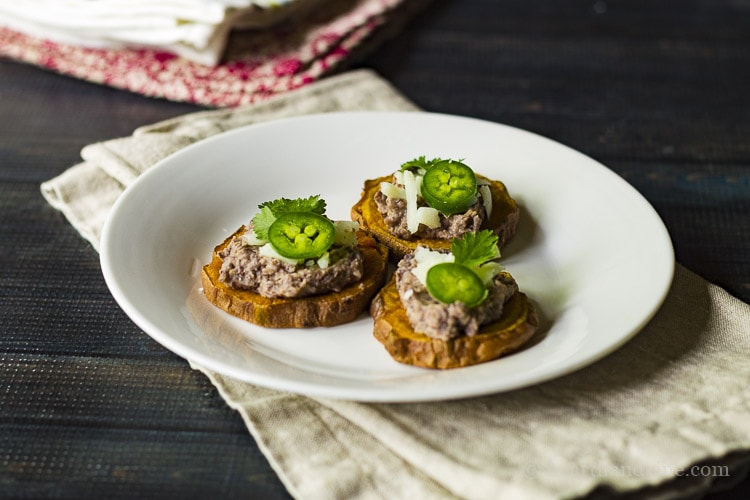 Appetizer of sweet potato rounds with black bean dip, manchego cheese, jalapeno and cilantro.