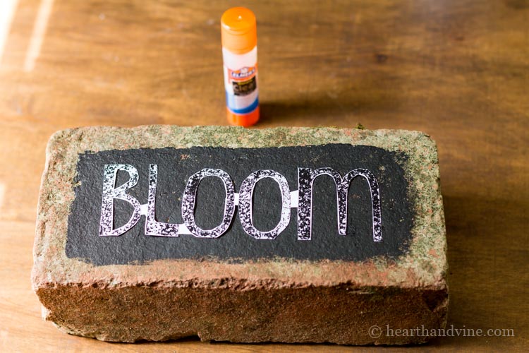 Brick with black paint and the word bloom glued on.