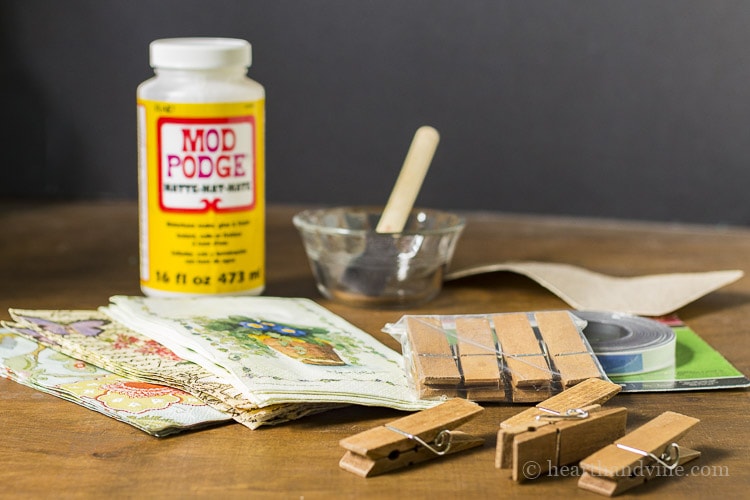 Materials for magnetic clothespins including napkins, mod podge, clothespins and sandpaper.