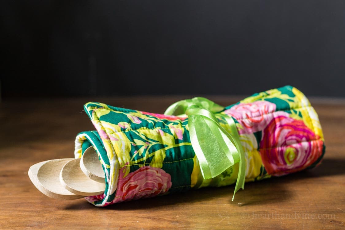 Fat quarter trivet rolled up with wooden spoons and tied with a green ribbon.