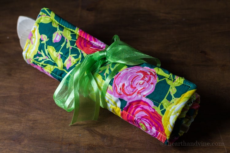 Gift set of trivet and spoons rolled and wrapped with a green ribbon.