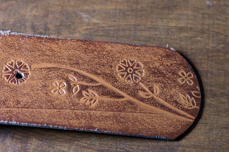 End of leather belt with floral engraving.