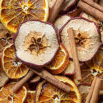 Close up view of natural potpourri made up of dried apple and orange slices and cinnamon sticks.