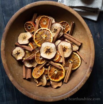 A bowl of homemade potpourri with dried apples, oranges and cinnamon sticks.