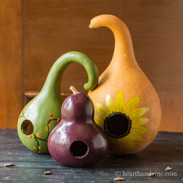 Three decorative birdhouse gourds on a table.