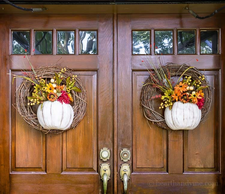 A pumpkin wreath made with half a pumpkin that acts as a vase for faux flowers is a great way to add beautiful fall color to your front door.